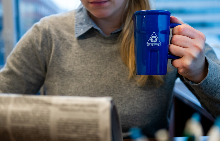 A person holding a mug that says we recycle