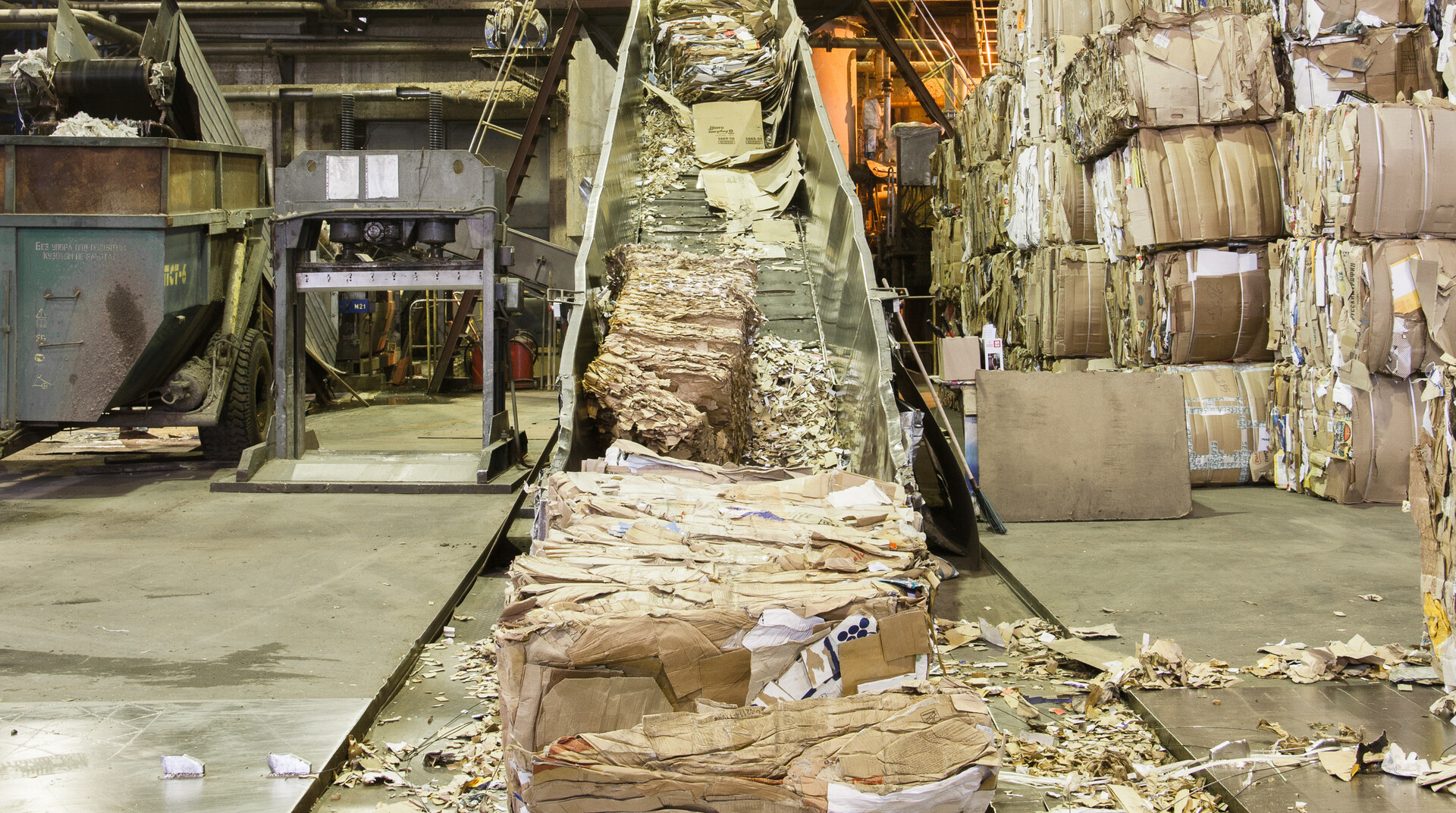 Bales of recycled cardboard going into a pulper at a paper mill.