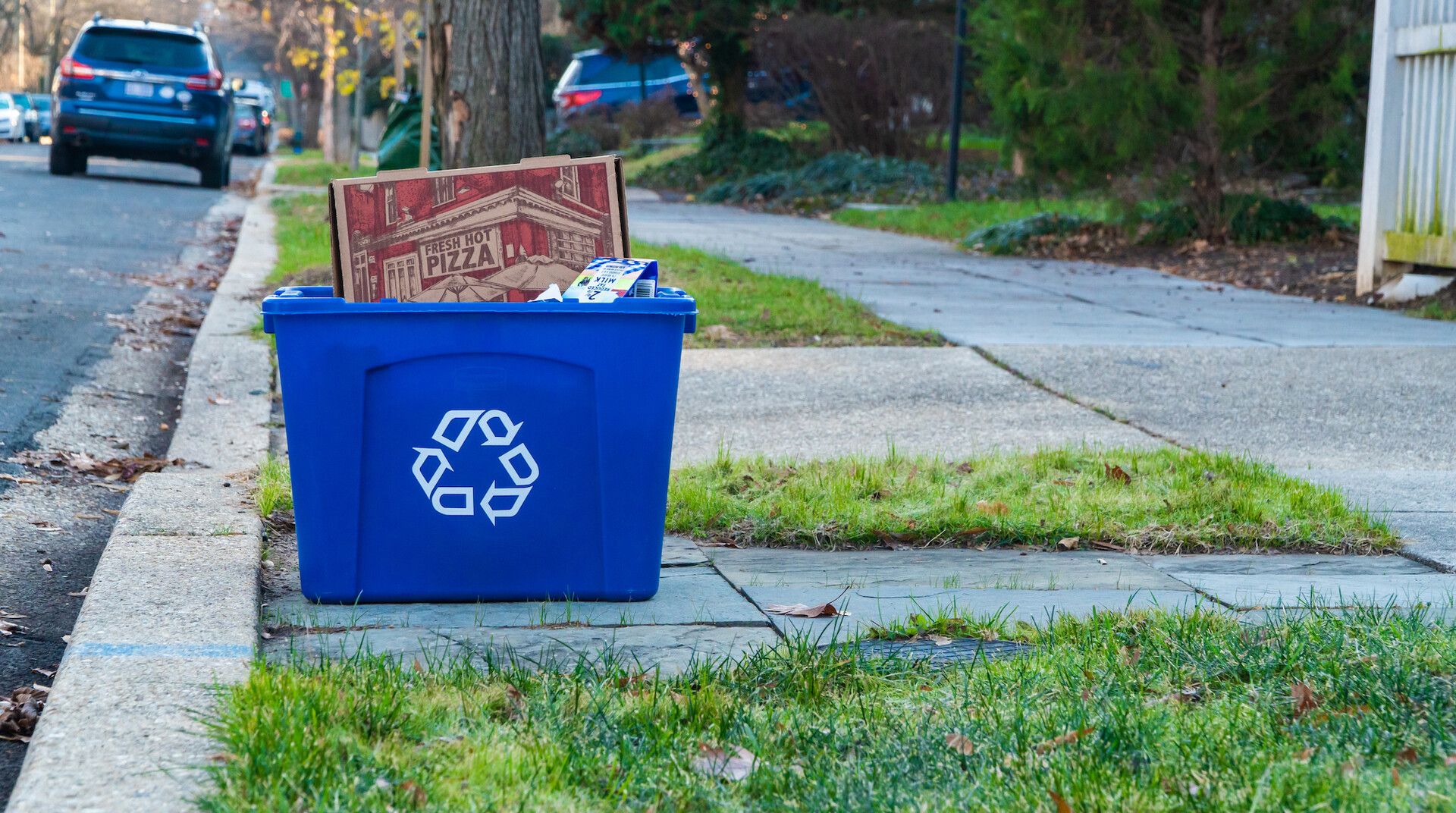 Recycling bin on residential curb with pizza box and paper packaging 