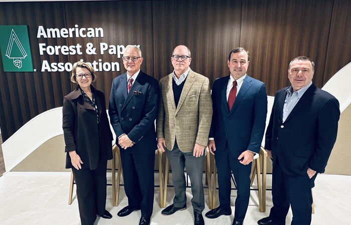 1 woman and 4 men in suits standing in front of a sign that says "The American Forest & Paper Association"