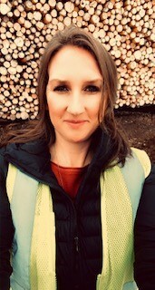 Denise Weinberger of Johnson Timber standing in front of a wood pile